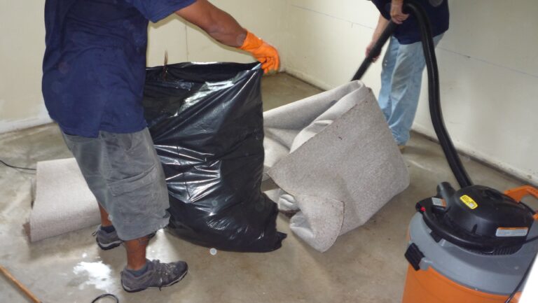 Technicians removing sewage-affected flooring and exposing contaminated wall areas during residential sewage backup cleanup in Sarasota Florida