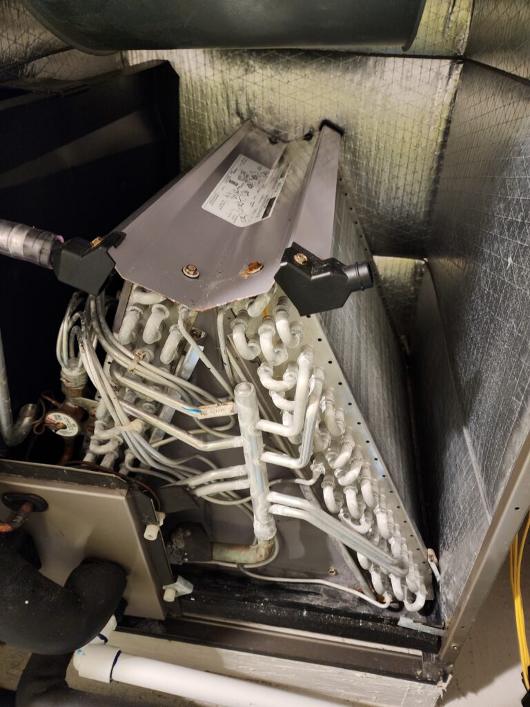 Dust and debris inside the lower section of a residential HVAC air handler during professional cleaning in Bradenton, Florida.