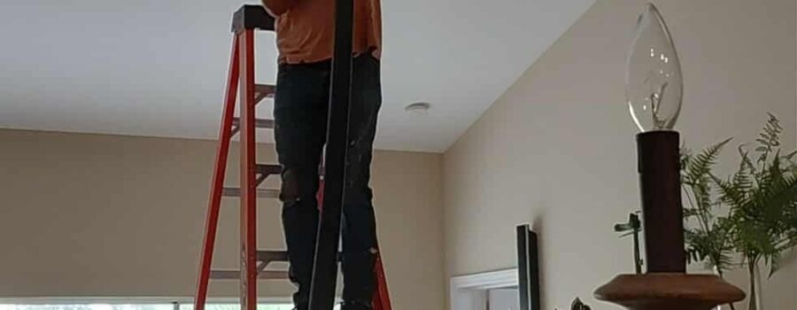 Technician using specialized duct-cleaning equipment through a ceiling HVAC access opening in a Sarasota home.